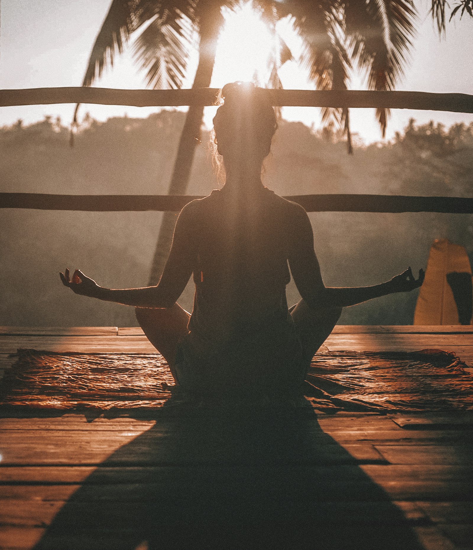 A person sitting quietly beside water in soft sunset light